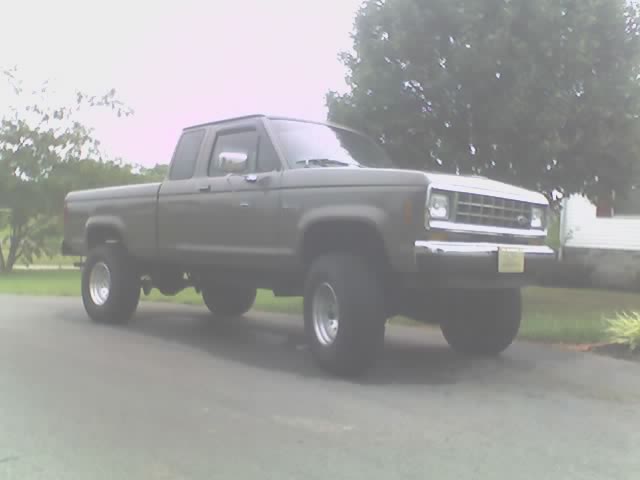 Gray lifted Ford Ranger extended-cab pickup on chrome wheels parked on a street