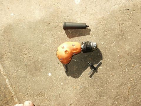 1996 Ford Bronco - A right angle drill and its chuck key are laid out on a concrete surface.