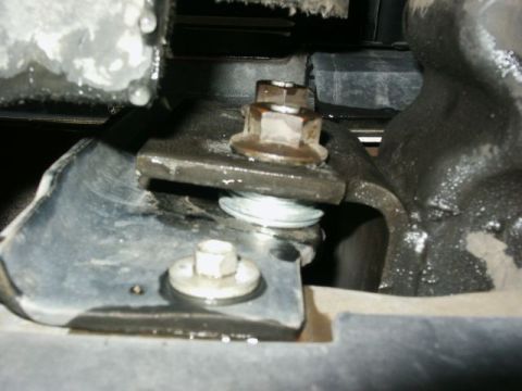 1996 Ford Bronco - A close-up view shows a bolted bracket and washer assembly, likely part of a vehicle's suspension system.