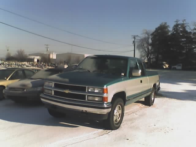 Green and silver Chevrolet extended-cab pickup, front three-quarter, in a snowy lot