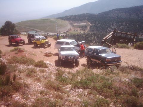 1978 Ford Bronco - Several off-road vehicles are gathered on a dirt road in a mountainous area.