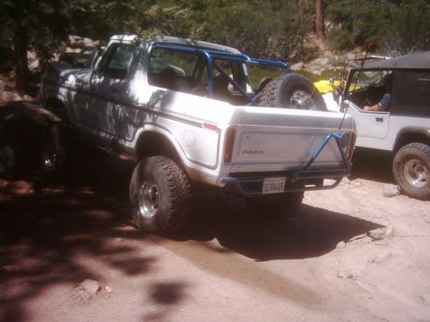 1978 Ford Bronco - White 1978 Ford Bronco with a blue roll cage and spare tire in the bed, parked next to a Jeep.