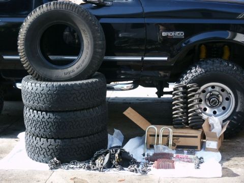 1996 Ford Bronco - 1996 Ford Bronco parked next to a stack of tires and suspension components, possibly for an upgrade.