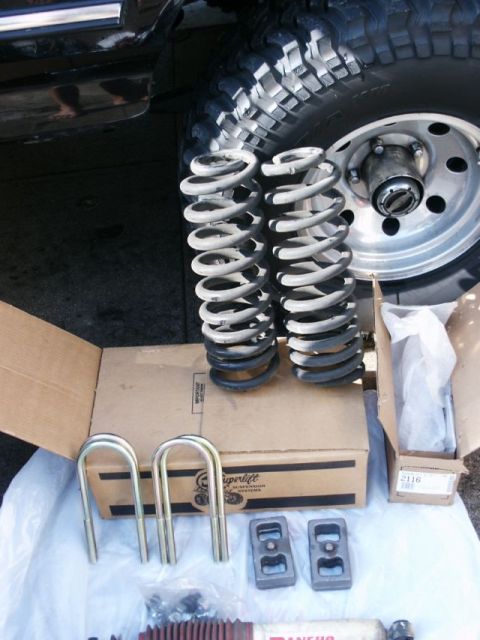 1996 Ford Bronco - Suspension parts laid out on the ground, with a vehicle's tire and fender visible in the background.