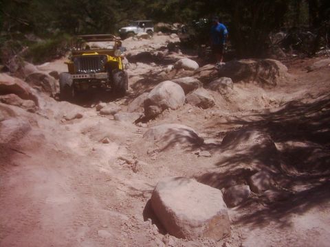 1978 Ford Bronco - Multiple off-road vehicles navigate a challenging, rocky terrain on a sunny day.