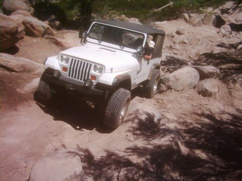 1978 Ford Bronco - A white Jeep Wrangler navigates a rocky off-road trail.