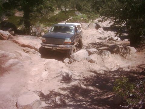 1978 Ford Bronco - This dark blue SUV navigates a challenging rocky trail, appearing to be from the 1992 model year.