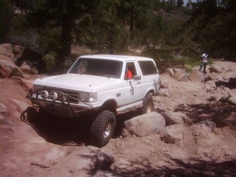 1978 Ford Bronco - White Ford Bronco tackling a rough, rocky off-road path.