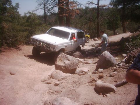 1978 Ford Bronco - A white Ford Bronco tackles a challenging rocky path, with another vehicle visible in the background.