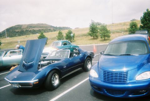 1972 Ford Ranchero - Two blue cars, a Corvette Stingray and a PT Cruiser, parked side-by-side at an outdoor event.