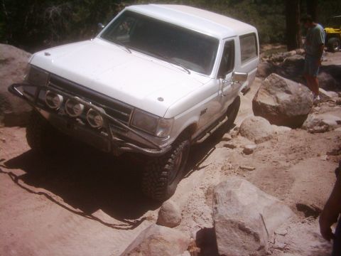 1978 Ford Bronco - White SUV navigating a difficult rocky trail, with another vehicle in the background.