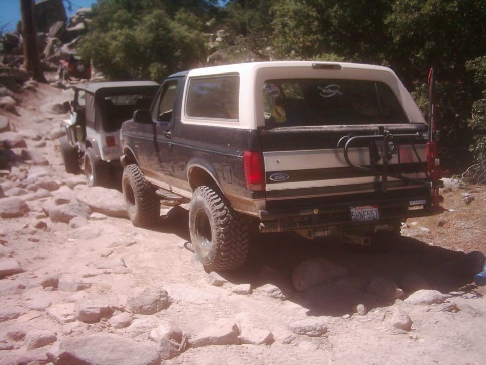 Black and white Ford Bronco with off-road tires on a rocky trail