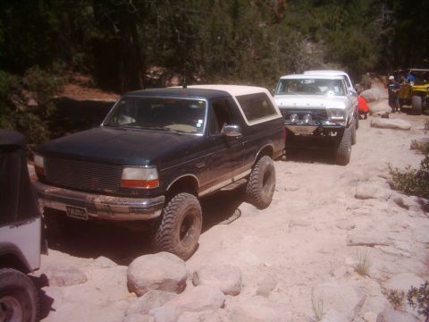 1978 Ford Bronco - A convoy of SUVs navigates a challenging rocky trail, led by a dark green Ford Bronco.