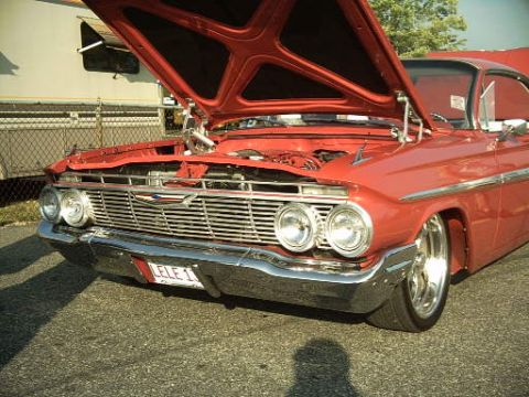 1990 Ford LTD Crown Victoria - Front view of a red 1961 Chevrolet Impala with its hood open, revealing the engine bay.
