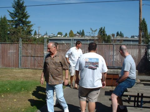 1999 Ford Crown Victoria - A group of men are seen outdoors on a sunny day, with one person wearing a t-shirt that displays a graphic of several cars.