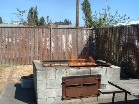 1999 Ford Crown Victoria - Outdoor barbecue pit made of concrete blocks with a fire burning inside.