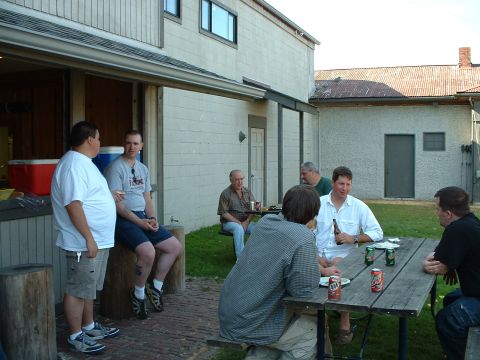 1999 Ford Crown Victoria - Several men are gathered outdoors near a building, some sitting at a picnic table and others standing.