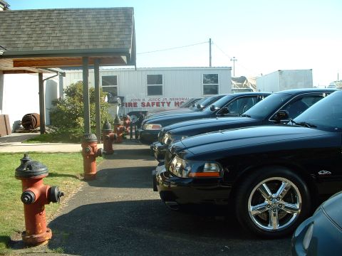 1999 Ford Crown Victoria - Several black 1999 Ford Crown Victoria sedans are parked in front of a building labeled 'Fire Safety'.