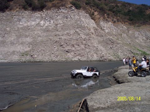 1985 Ford Bronco - Off-roading scene with a Jeep Wrangler navigating through a muddy area.