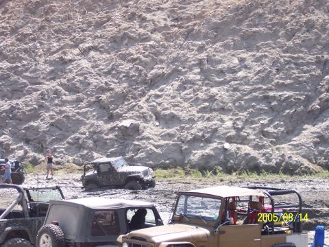 1985 Ford Bronco - Off-road vehicles navigate a muddy terrain, with a large dirt embankment providing a backdrop. The scene is dated 2005/08/14.