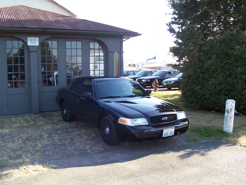 Black 2003 Ford Crown Victoria parked in front of a building with other cars in the background