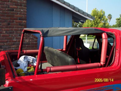 1985 Ford Bronco - Interior view of a red off-road vehicle with racing seats and a roll cage.