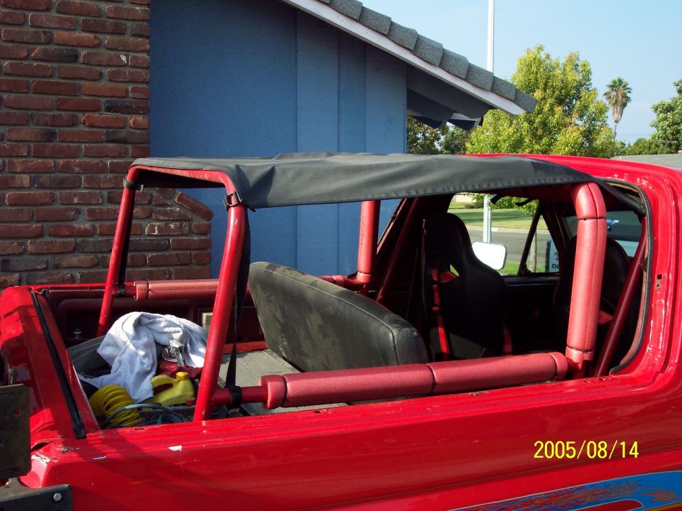 Red Ford Bronco with top off showing red roll cage and black bikini top