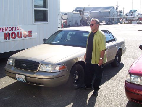 2003 Ford Crown Victoria - A man poses next to a tan 2003 Ford Crown Victoria, with another vehicle visible to the right.