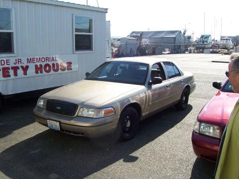 2003 Ford Crown Victoria - Gold 2003 Ford Crown Victoria parked next to a red car at a waterfront location.