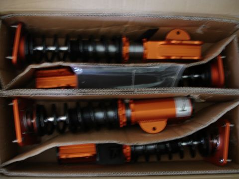 1989 Mazda MX-6 - A box contains new suspension parts, possibly for a car's front and rear.