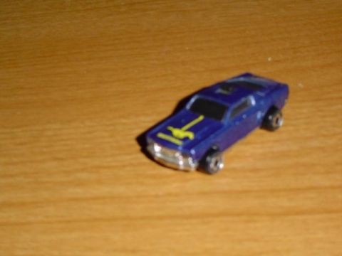 1979 Ford Bronco - A blue toy car with yellow racing stripes sits on a wooden table.