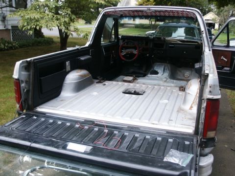 1982 Ford Bronco - The interior and bed of a 1982 Ford Bronco are visible with the tailgate down, showing exposed flooring and bed liner.