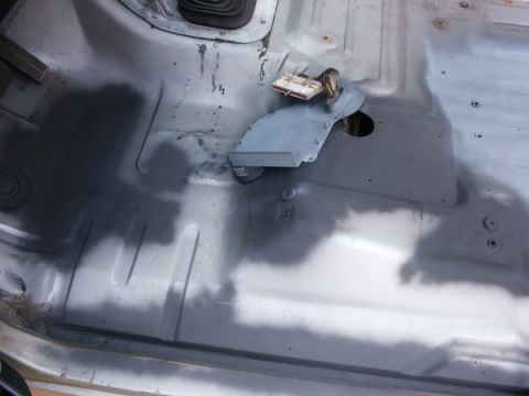 1982 Ford Bronco - Interior floor of a vehicle after spray-in liner application, with visible wiring and some dark spots.
