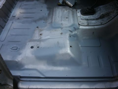 1982 Ford Bronco - The bare metal interior floor of a vehicle, showing the floor pan and shifter boot, likely before a spray-in liner application.