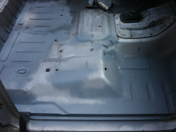 Vehicle interior floor with exposed metal and shifter boot