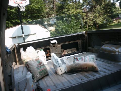 1982 Ford Bronco - Pickup truck bed interior view showing bags of material and a basketball hoop outside.