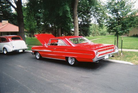 1972 Ford Ranchero - A bright red 1964 Ford Galaxie 500 coupe is parked with its hood open, alongside another classic car.