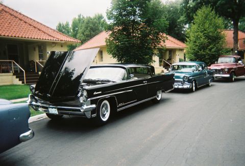 1972 Ford Ranchero - Three classic cars are parked in a row on a street, with the front car's hood open.