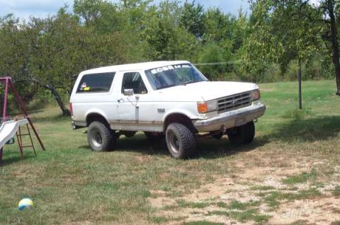 1988 Ford Bronco - This 1988 Ford Bronco is seen parked on a grassy area with trees in the background.