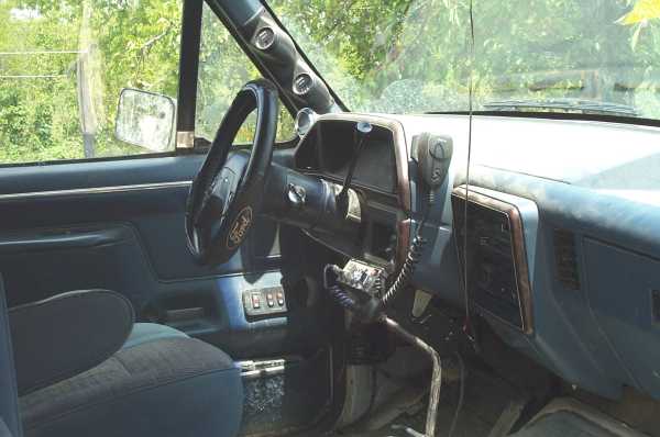 Blue Ford truck interior with Ford steering wheel, woodgrain dash and CB radio with mic