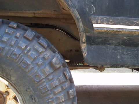 1988 Ford Bronco - Close-up view of the wheel well and fender trim of a vehicle, showing suspension and a large tire.