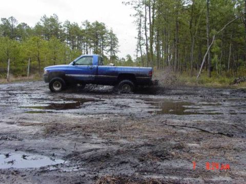 1995 Dodge 1500 - Blue 1995 Dodge 1500 pickup truck kicking up mud while driving off-road.