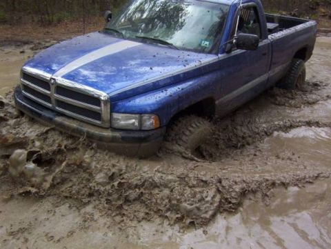 1995 Dodge 1500 - This blue Dodge 1500 is deep in the mud, with its front tire almost completely covered.