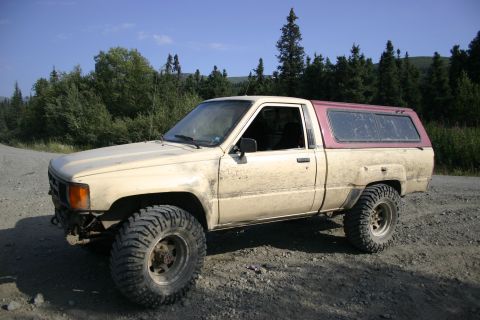2003 Jeep TJ - This older model Toyota pickup truck is equipped with off-road tires and a camper shell, suggesting it is used for outdoor adventures.