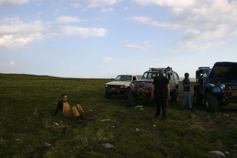 2003 Jeep TJ - A group of off-road enthusiasts and their vehicles gather in a scenic, grassy landscape.