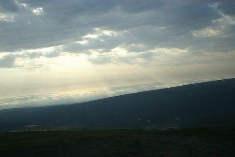 2003 Jeep TJ - Sunlight streams through clouds over a vast, shadowed landscape with a distant tree line.