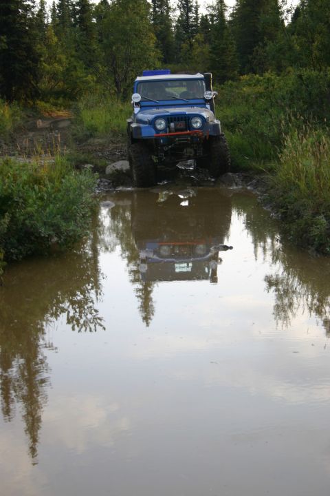 2003 Jeep TJ - Blue 2003 Jeep TJ navigates a water obstacle on a wooded trail.