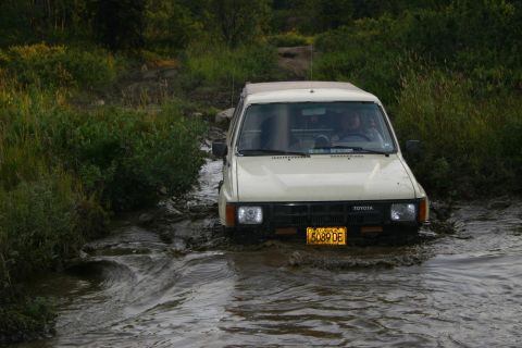 2003 Jeep TJ - Toyota pickup truck navigating a water crossing on an off-road trail.