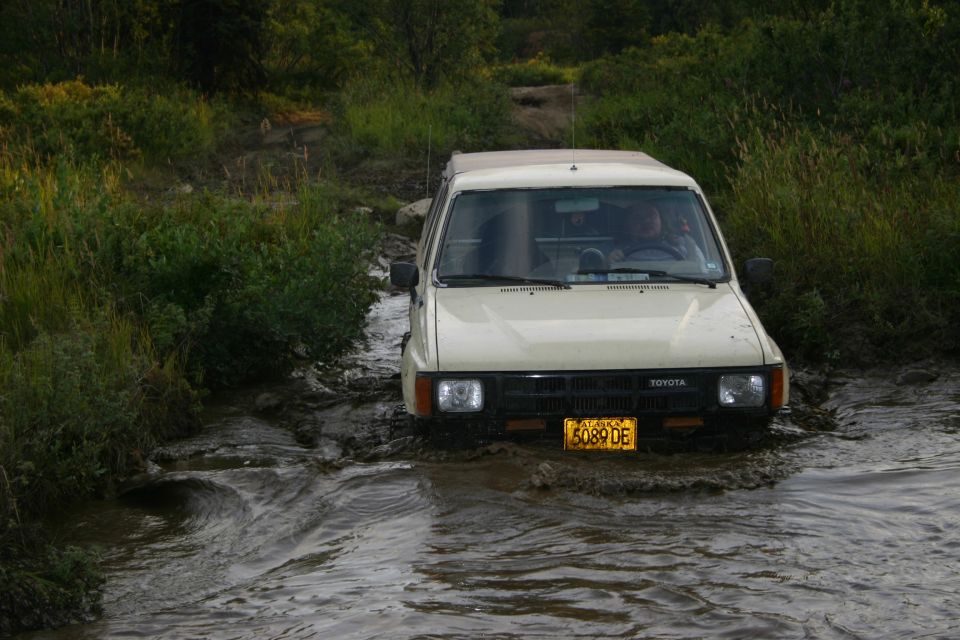 Toyota pickup truck with yellow license plate driving through muddy water