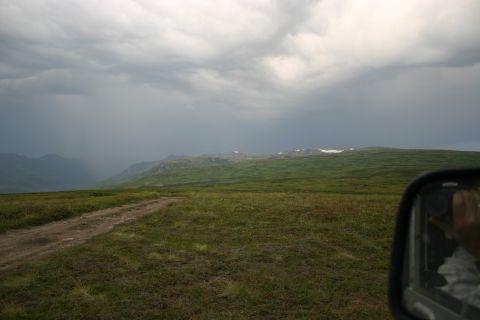 2003 Jeep TJ - A dirt road winds through a vast, grassy landscape under a dramatic, cloudy sky.